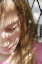 Close-up of girl (6-7) in dappled sunlight