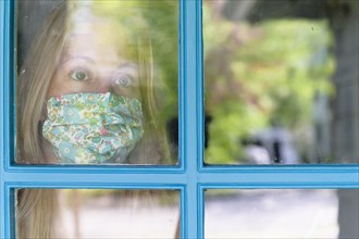 Woman in face mask looking through window