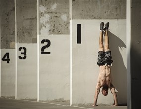 Man doing handstand next to wall