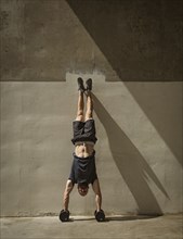 Man doing handstand next to wall