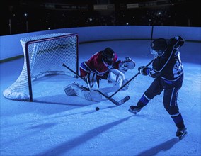 Hockey goalie defending net against forward