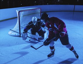 Hockey goalie defending net against forward