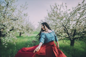 Young woman dancing in blooming orchard