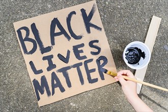 Woman's hand painting Black Lives Matter sign on cardboard,,