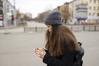 Russia, Chelyabinsk, Young woman using smartphone in city