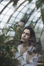 Ukraine, Crimea, Young woman looking at plant in greenhouse