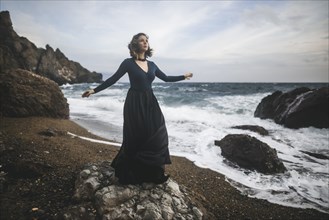 Ukraine, Crimea, Young woman standing on rocky beach