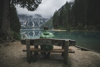 Italy, Man sitting on bench looking at Pragser Wildsee,