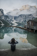 Italy, Woman sitting by Pragser Wildsee in Dolomites,