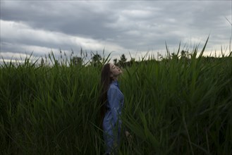 Russia, Omsk, Young woman in tall grass
