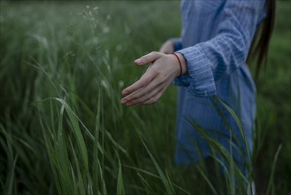 Russia, Omsk, Mid section of woman in tall grass