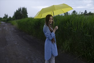 Russia, Omsk, Portrait of young woman with umbrella on dirt road