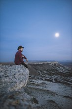 Ukraine, Crimea, Hiker sitting on edge of steep cliff near White Mountain