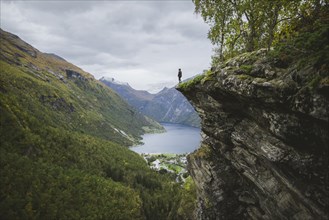 Norway, Geiranger, Man standing on edge of steep cliff above Geirangerfjord