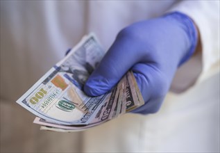 Person in surgical glove holding money