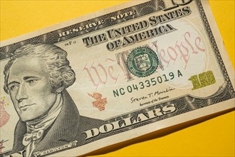 Close-up of US ten dollar bill on yellow