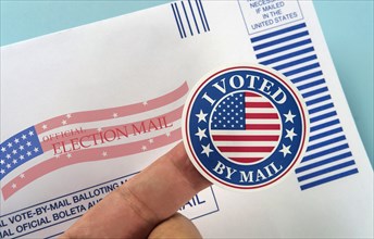 Human finger holding sticker above voting mail,,