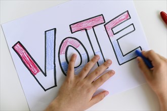 Child's hands coloring Vote sign,,