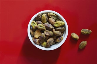 Pistachios in bowl on red background