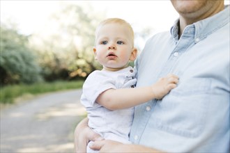 Outdoor portrait of baby boy carried by his father outdoors