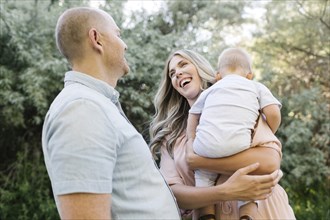 Happy parents with baby son laughing in garden