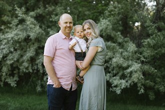 Outdoors portrait of parents with baby son standing in garden