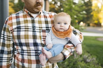 Outdoor portrait of baby boy carried by father