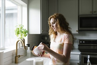 Woman cleaning jar in kitchen