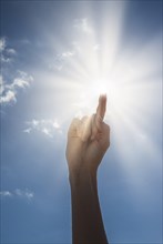 Woman's hand pointing towards sun