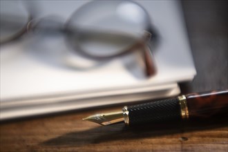 Retro eyeglasses and pen on stack of paper