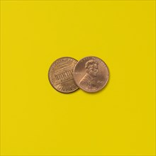 Front and back of two pennies on yellow background