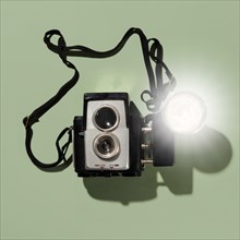 Retro camera with blub flash on green background