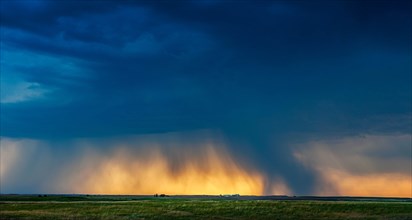 USA, South Dakota, Sun breaking through storm clouds and rain at sunset