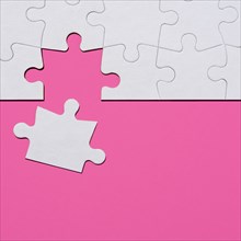 Last puzzle piece in jigsaw puzzle on pink background