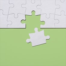 Last puzzle piece in jigsaw puzzle on green background