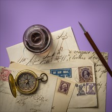 Antique ink well and old letters on purple background