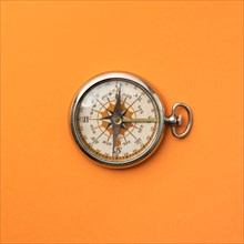 Antique compass on orange background