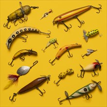 Arranged group of vintage fishing lures on yellow background