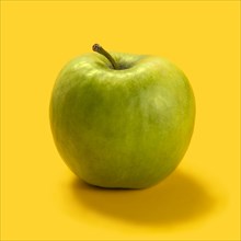 Green apple against yellow background