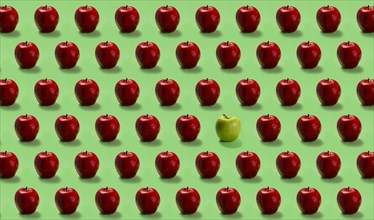 Group of red apples and one green on green background