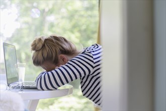 Woman using laptop and falling asleep