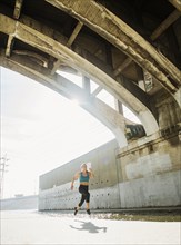 USA, California, Los Angeles, Sporty woman running underneath bridge