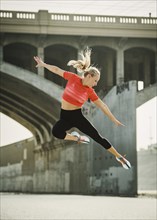 USA, California, Los Angeles, Sporty woman jumping in urban setting