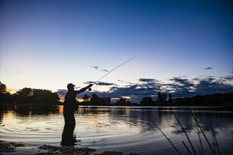 USA, Utah, Salem, Silhouette of man fly fishing in lake at dusk