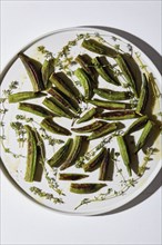 Roasted okra pieces with thyme on plate