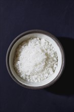 Sea salt in bowl on blue background