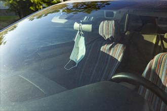Face mask hanging from rear view mirror inside car