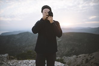 Italy, Liguria, La Spezia, Man using camera in mountains