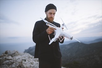 Italy, Liguria, La Spezia, Man at mountain top holding drone