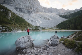 Italy, South Tyrol, Cortina d Ampezzo, lake Sorapis, Men standing on top of rock formations looking at view